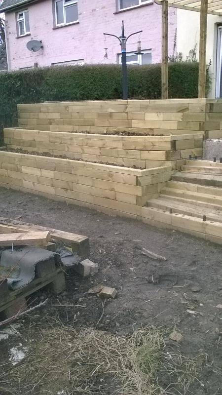Terraced raised beds with steps to patio and with pond and seat.