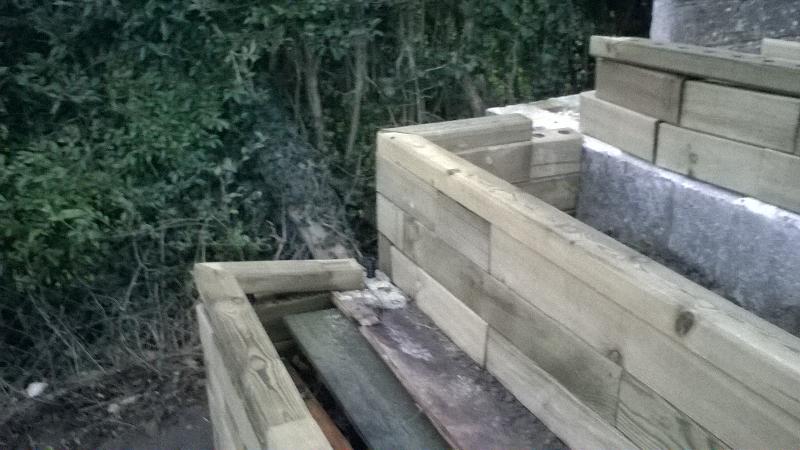 Terraced raised beds with steps to patio and with pond and seat.