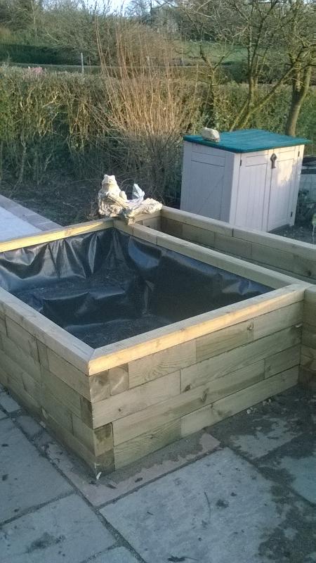 Terraced raised beds with steps to patio and with pond and seat.
